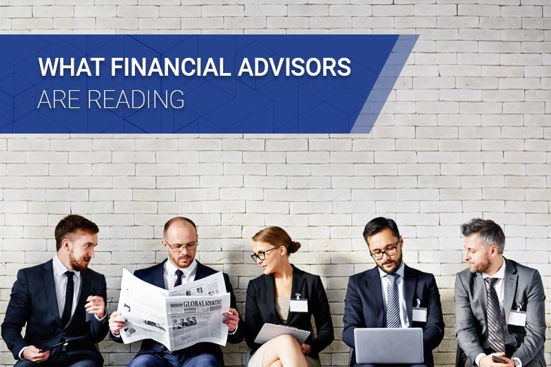 Financial advisors in front of brick wall reading news